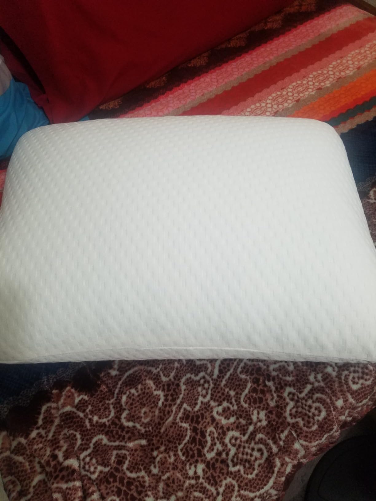 A white Molblly Standard Pillow rests on a bed beside a pair of shoes, showcasing its comfort in use for a product review.