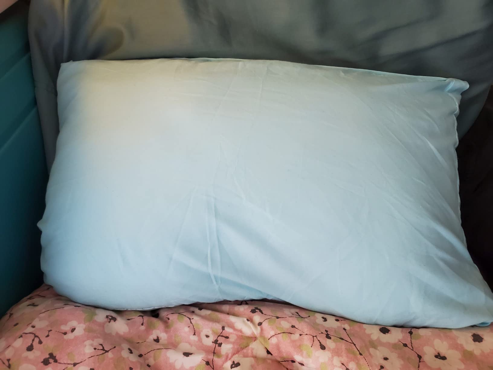 The LINENSPA Memory Foam Pillow is placed on a bed adorned with a blue cover, highlighting its comfort in a relaxing environment.