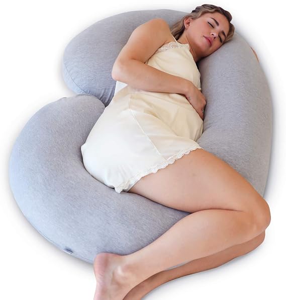 A woman peacefully sleeps on a heart-shaped pillow, the Pharmedoc Pregnancy Pillow, providing comfort and support.